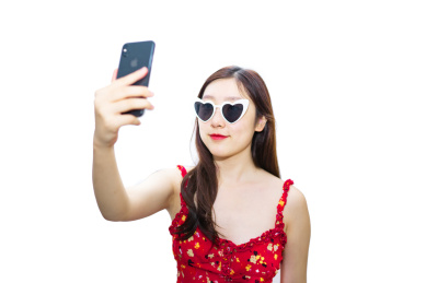 夏季一个中国女孩拿着手机戴着墨镜正在自拍拍照
