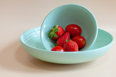 红色的新鲜水果草莓和小番茄放在绿色的碗里