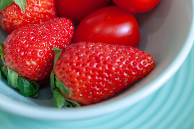 红色的新鲜水果草莓和小番茄放在绿色的碗里