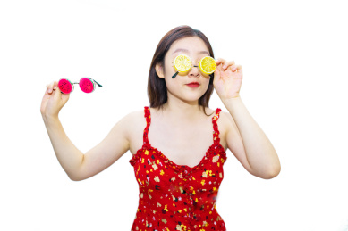 一个中国美女站在白色背景下挑选着柠檬和西瓜眼镜