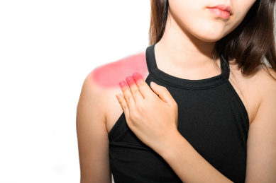 一个亚洲女性揉着自己疼痛酸痛的肩膀