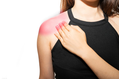 一个亚洲女性揉着自己疼痛酸痛的肩膀