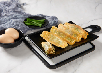 黑色盘子里金黄外皮的韭菜鸡蛋锅贴