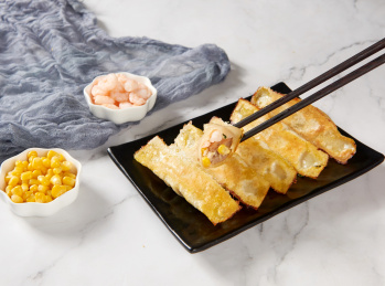 黑色盘子里金黄外皮的虾仁玉米锅贴