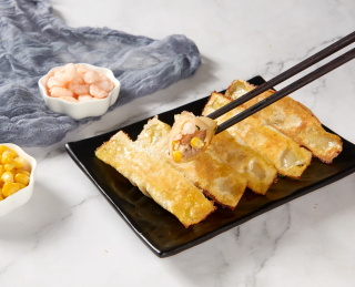 黑色盘子里金黄外皮的虾仁玉米锅贴