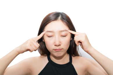 一个亚洲女人摸着自己的疼痛头痛头疼的脑袋,感觉很难受很烦躁