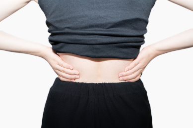 一个摸着揉着自己疼痛而又酸痛的腰的腰间盘突出的中国亚洲女人