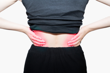 一个摸着揉着自己疼痛而又酸痛的腰的腰间盘突出的中国亚洲女人