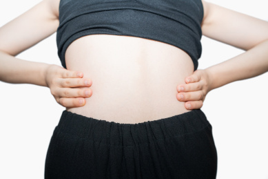 一个摸着揉着自己疼痛而又酸痛的腰的腰间盘突出的中国亚洲女人