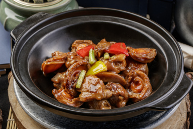 黑色砂锅装的砂锅鲍鱼鸡块摆放在樟木砧板上