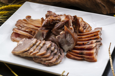 方形瓷盘装的卤肉拼盘摆放在黑色背景上