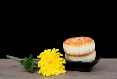 桌子上中秋节的月饼和一朵黄菊花