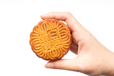 白色背景中 手拿着一个月饼