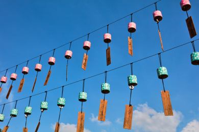 两排许多粉色和粉蓝色陶瓷风铃在蓝色天空背景里