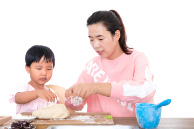 白背景前年轻妈妈正在教小女孩学习做面点月饼