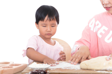 白背景前年轻妈妈正在教小女孩学习做面点月饼