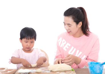 白背景前中国妈妈正在教自己的孩子做月饼