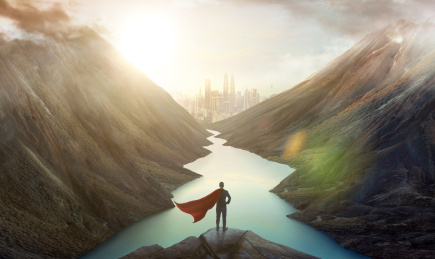 坚强努力的商人站在山顶山上俯瞰山崖中城市天际线