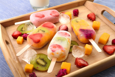 蓝色背景上木托盘里的水果雪糕冰棍