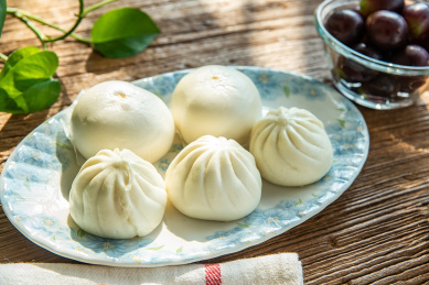 木桌面上的营养早餐一盘包子馒头和葡萄