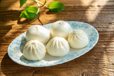 木桌面上的营养早餐一盘包子和馒头   