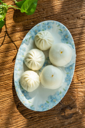木桌面上的营养早餐一盘包子和馒头   