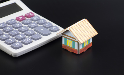 黑色背景中放着小房子和计算器