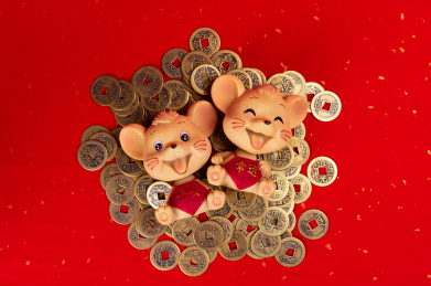 烫金红纸背景上躺在一堆铜钱上的欢快的小老鼠