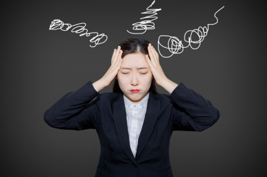 灰黑色背景下一个西服正装女上班族头疼头痛压力大焦虑的捂着头烦恼