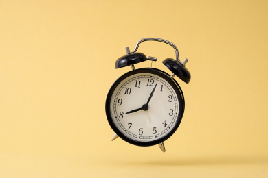 黄色背景前，跳跃的黑色闹钟