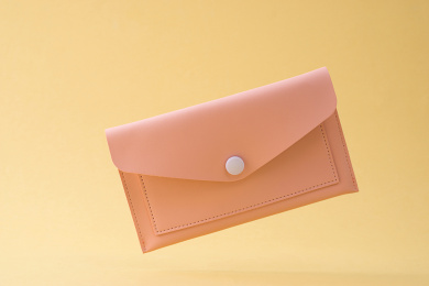 黄色背景前，掉落的粉色时尚小皮包