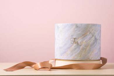 粉色背景前，拆开丝带的香槟色蛋糕盒