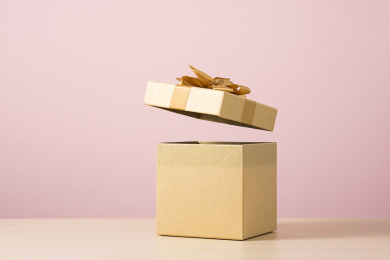 粉色背景前，打开盖子的金色礼盒