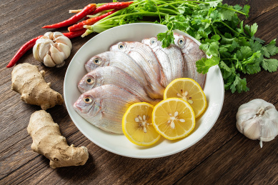 一碟新鲜红鲷鱼和香料食材在木板背景上 