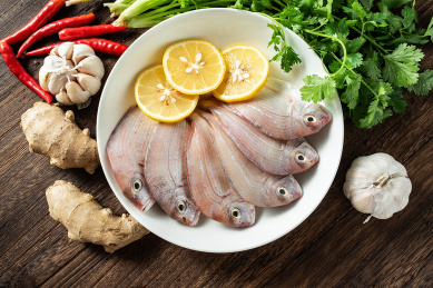 一碟新鲜红鲷鱼和香料食材在木板背景上 