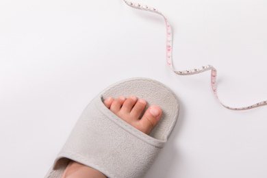 一只大拖鞋里有只小脚，鞋边还有测量皮尺