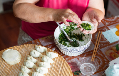 中国传统美食慈祥的外婆正在包着饺子和饺子馅