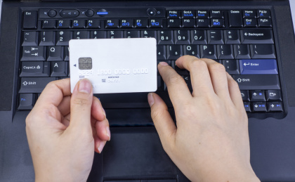 电脑键盘上放着的手里拿着银行卡