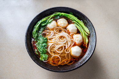 厨房台面上一碗鱼丸香辣汤粉