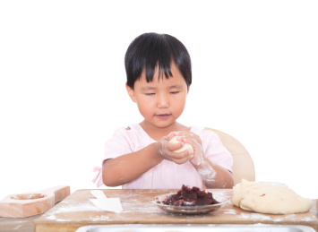 白背景前中国小女孩在制作中秋节的月饼