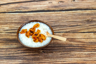 木纹桌面上瓷碗里的白米粥与萝卜干