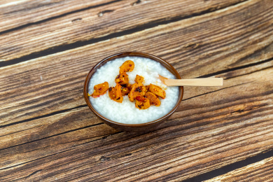 木纹桌面上瓷碗里的白米粥与萝卜干