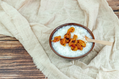 木纹桌面上瓷碗里的白米粥与萝卜干