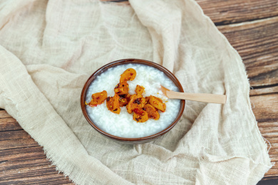 木纹桌面上瓷碗里的白米粥与萝卜干