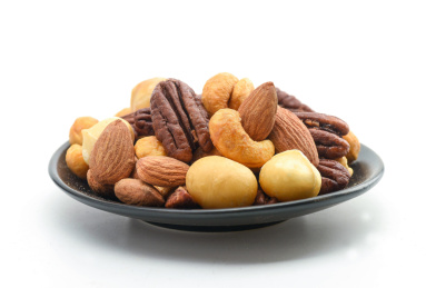 白色背景上黑盘子里的坚果果仁拼盘