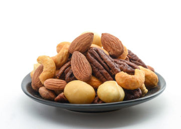 白色背景上黑盘子里的坚果果仁拼盘