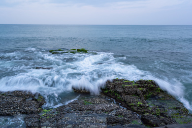 蔚蓝大海上的浪花和海岸边礁石