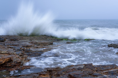 蔚蓝大海上的浪花和海岸边礁石