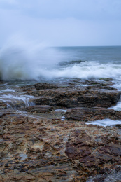 蔚蓝大海上的浪花和海岸边礁石