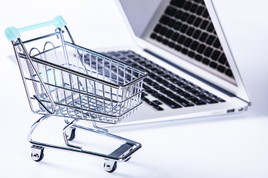 特写象征网上购物的小型购物车和笔记本电脑